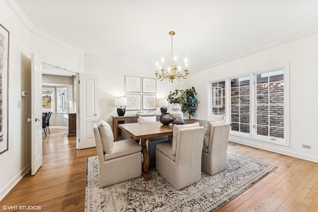 dining room featuring light wood-type flooring, baseboards, a notable chandelier, and ornamental molding