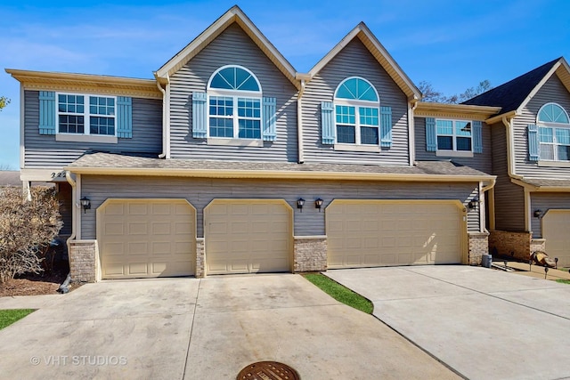 view of property featuring an attached garage, stone siding, and driveway