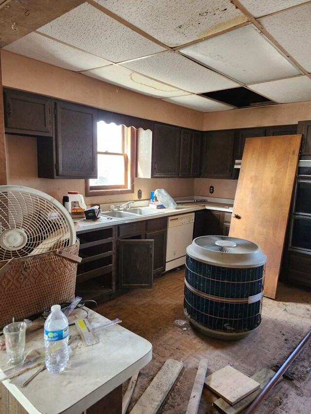 kitchen featuring light countertops, a paneled ceiling, white dishwasher, and a sink