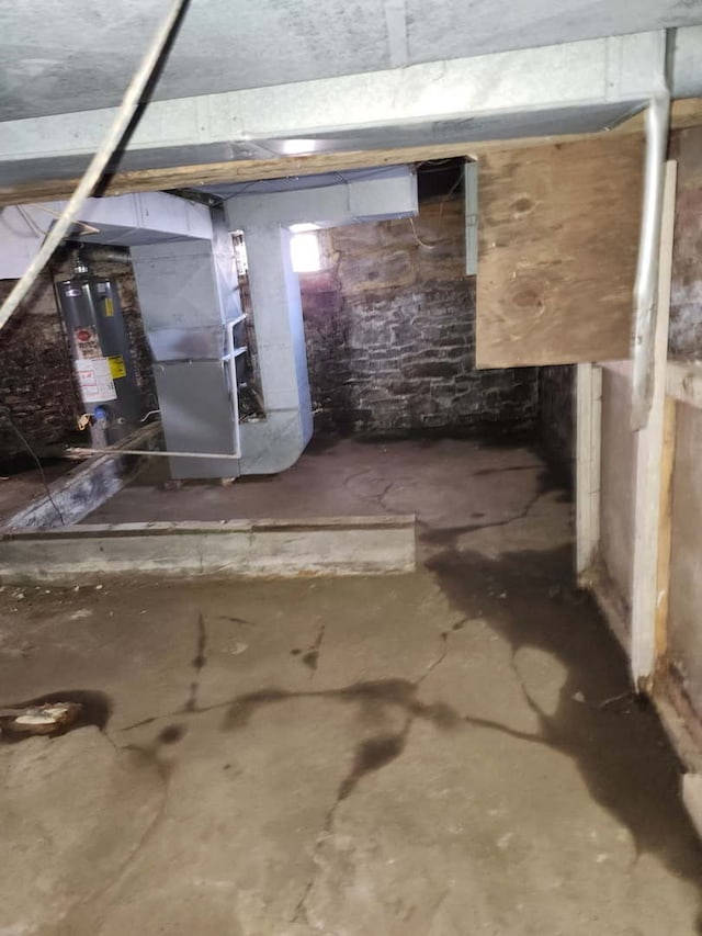 unfinished basement with gas water heater and heating unit