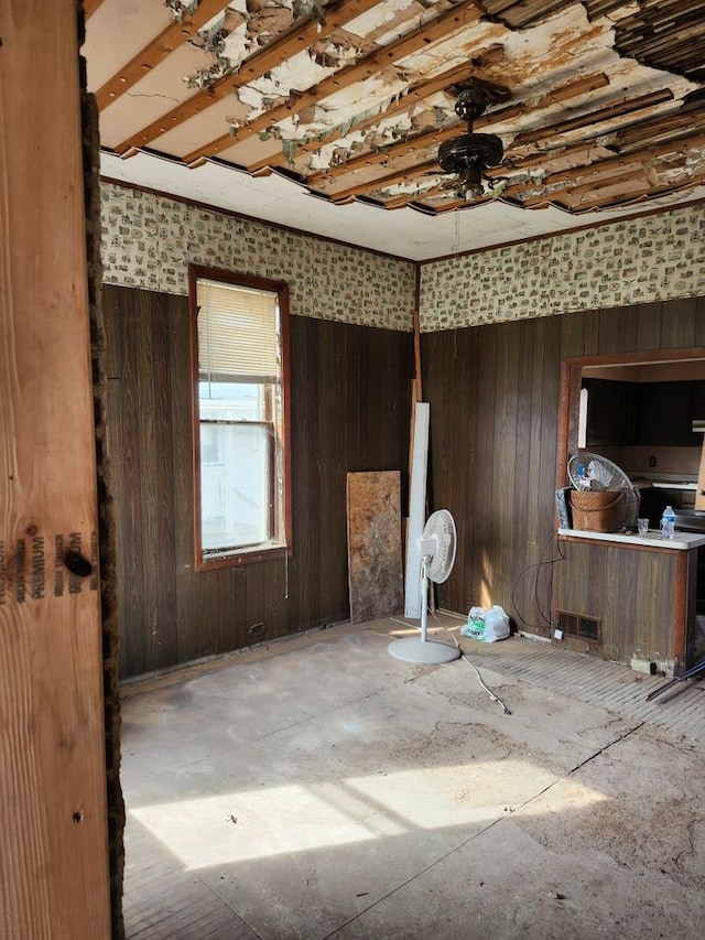 empty room featuring visible vents, wood walls, and a ceiling fan