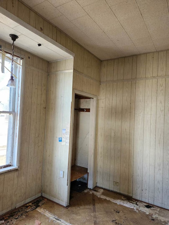 unfurnished bedroom featuring multiple windows and wood walls