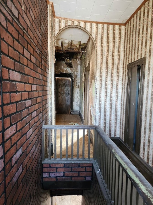 view of exterior entry featuring brick siding and a balcony