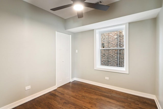 empty room featuring baseboards, dark wood finished floors, and a ceiling fan