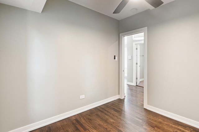 empty room with dark wood-type flooring, a ceiling fan, and baseboards