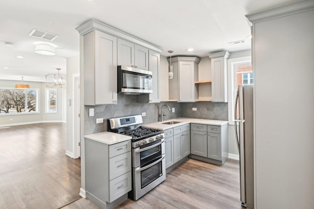 kitchen with visible vents, a sink, gray cabinets, appliances with stainless steel finishes, and open shelves