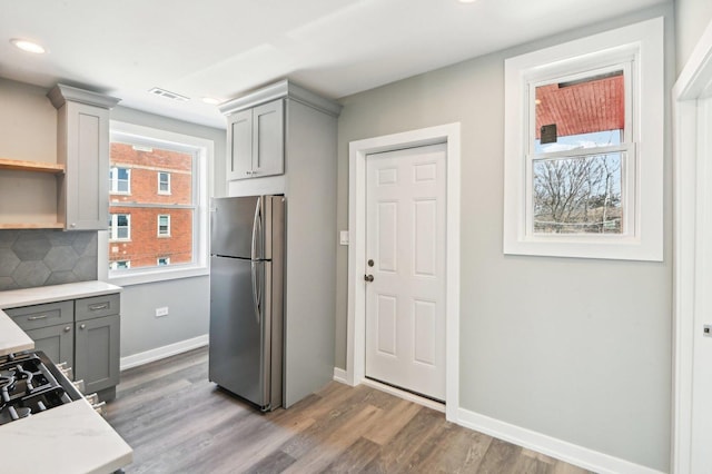 kitchen featuring tasteful backsplash, baseboards, gray cabinets, freestanding refrigerator, and wood finished floors