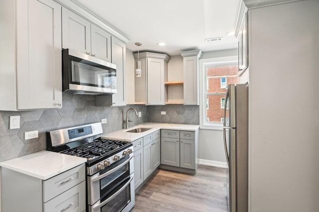 kitchen with open shelves, a sink, stainless steel appliances, light wood-type flooring, and backsplash