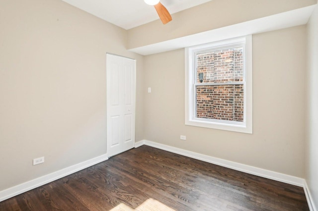 empty room featuring ceiling fan, baseboards, and dark wood-style floors