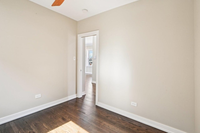 unfurnished room featuring dark wood finished floors, a ceiling fan, and baseboards