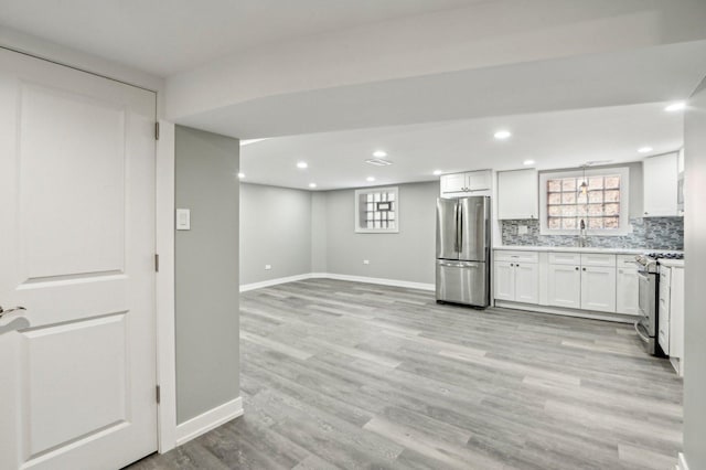 kitchen with light countertops, decorative backsplash, light wood-style flooring, stainless steel appliances, and a sink