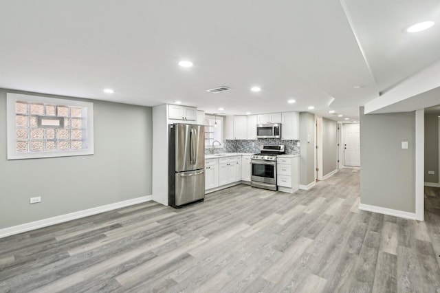 kitchen featuring light wood-type flooring, visible vents, a sink, tasteful backsplash, and appliances with stainless steel finishes