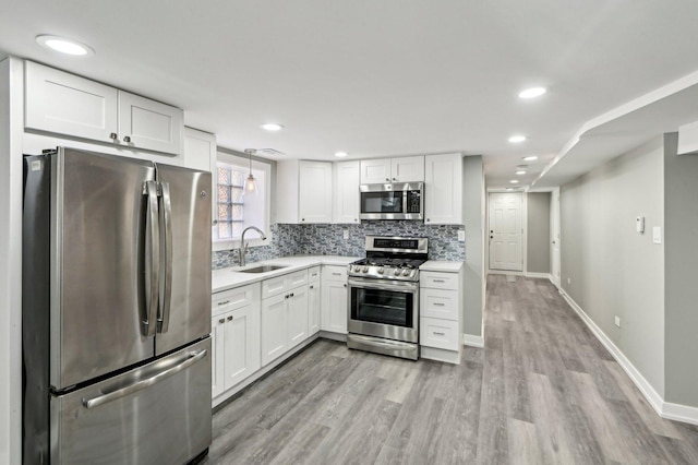 kitchen with a sink, stainless steel appliances, white cabinets, light countertops, and decorative backsplash