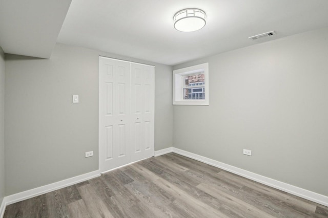 unfurnished bedroom featuring a closet, visible vents, baseboards, and wood finished floors