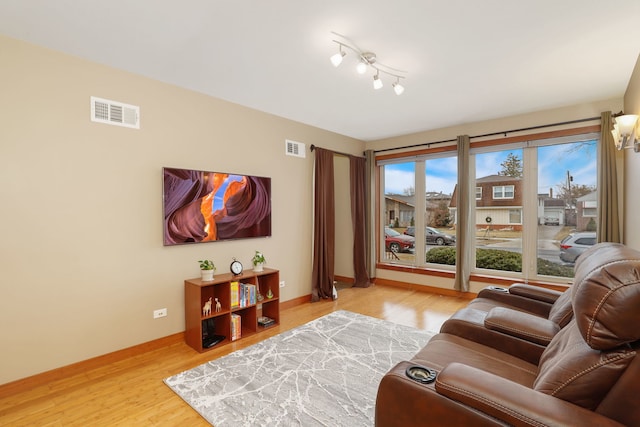 living area with wood finished floors, visible vents, and baseboards