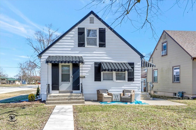 bungalow-style house with entry steps, a front lawn, and a patio area