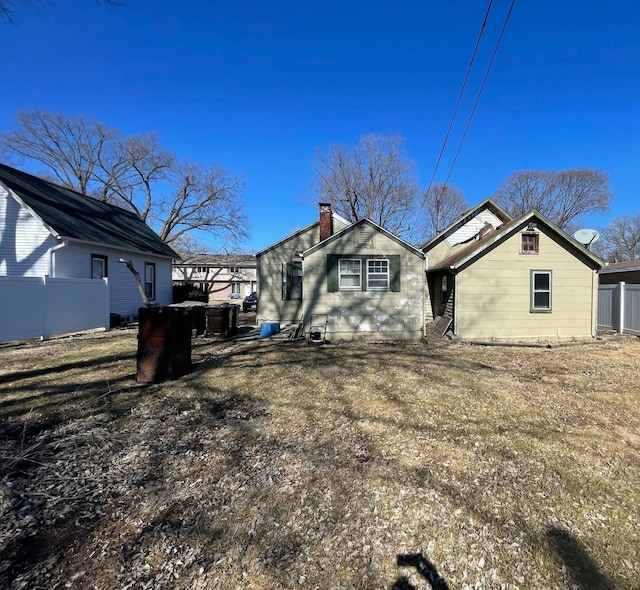 back of house featuring a chimney and fence