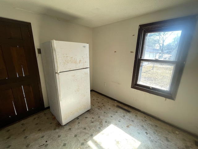 kitchen featuring visible vents, baseboards, and freestanding refrigerator