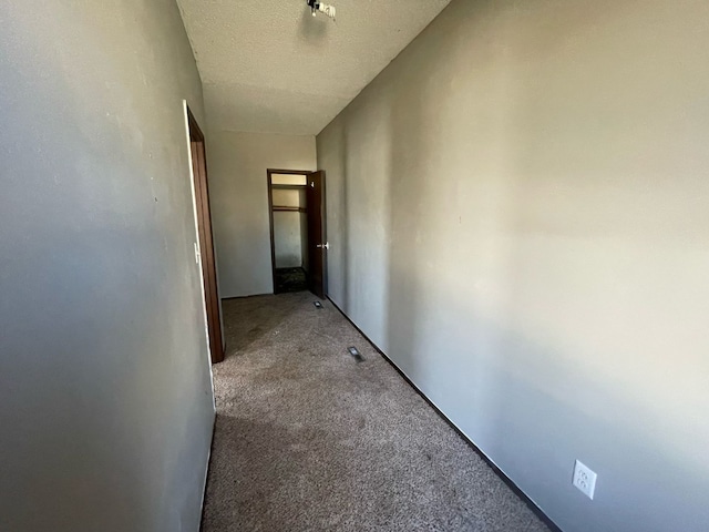 corridor with light carpet and a textured ceiling