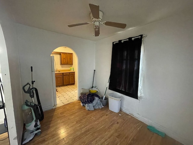 bedroom featuring a ceiling fan, wood finished floors, arched walkways, and ensuite bathroom