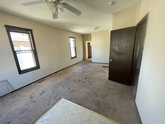 carpeted spare room with a textured ceiling, visible vents, and ceiling fan