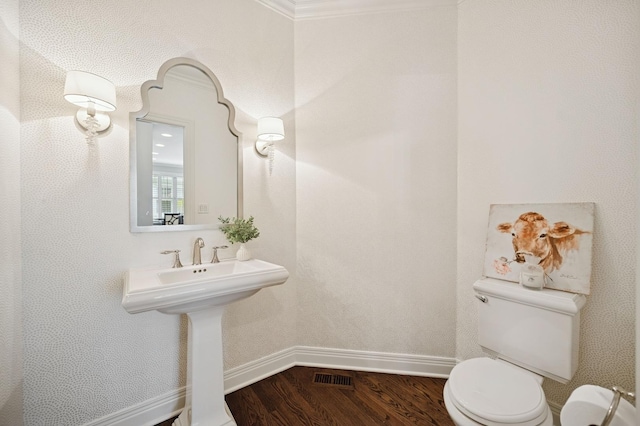 bathroom with toilet, wood finished floors, ornamental molding, visible vents, and baseboards
