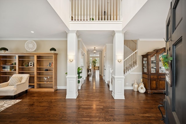 foyer with dark wood-style floors, stairway, crown molding, and ornate columns