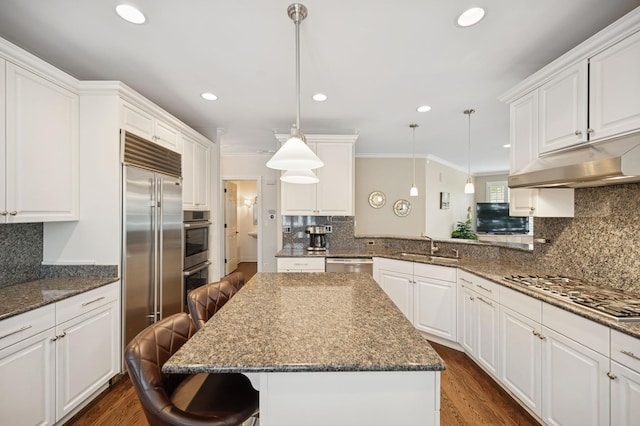 kitchen featuring a breakfast bar area, a sink, crown molding, tasteful backsplash, and appliances with stainless steel finishes