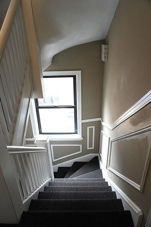 stairway with a decorative wall and wainscoting