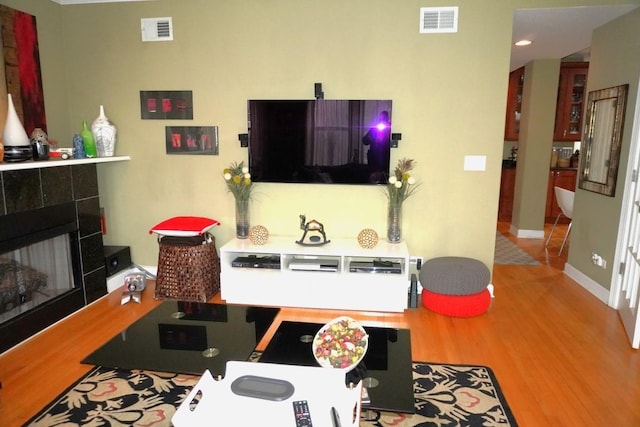 living area featuring visible vents, a tile fireplace, and wood finished floors