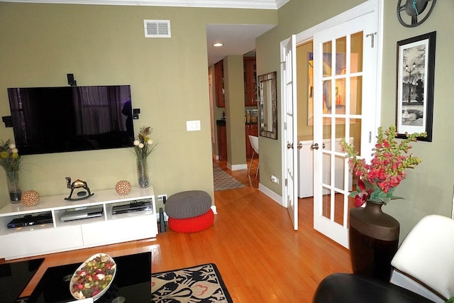 living room with visible vents, baseboards, and light wood finished floors