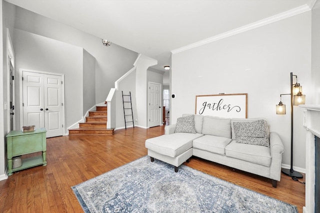 living area with stairway, wood finished floors, baseboards, and ornamental molding