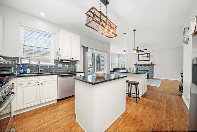 kitchen with a sink, appliances with stainless steel finishes, dark countertops, tasteful backsplash, and a center island