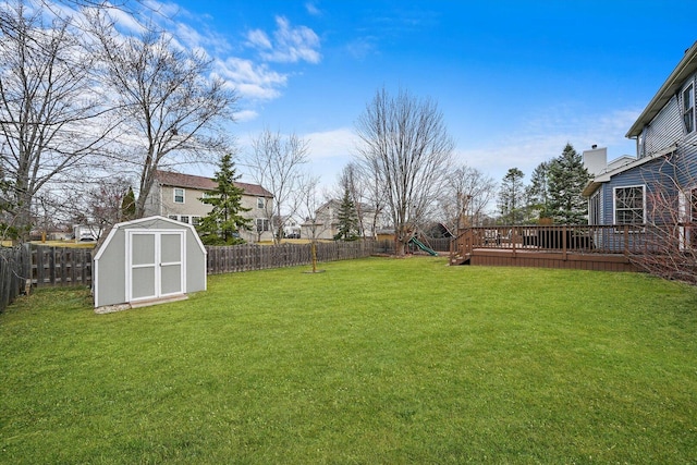 view of yard with a storage unit, a deck, a fenced backyard, a playground, and an outdoor structure