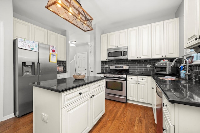 kitchen featuring decorative backsplash, dark wood-style floors, white cabinets, stainless steel appliances, and a sink