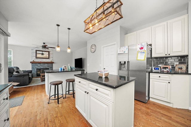 kitchen featuring a center island, open floor plan, light wood-style floors, stainless steel refrigerator with ice dispenser, and a ceiling fan