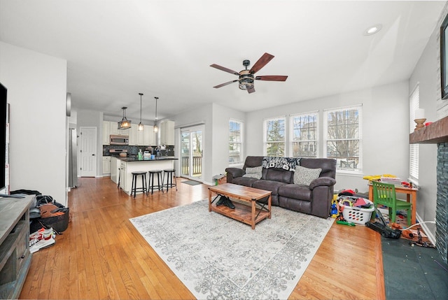 living area with recessed lighting, light wood-style flooring, baseboards, and ceiling fan