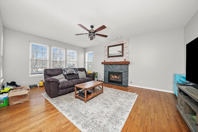 living room featuring a wealth of natural light, a fireplace, a ceiling fan, and wood finished floors