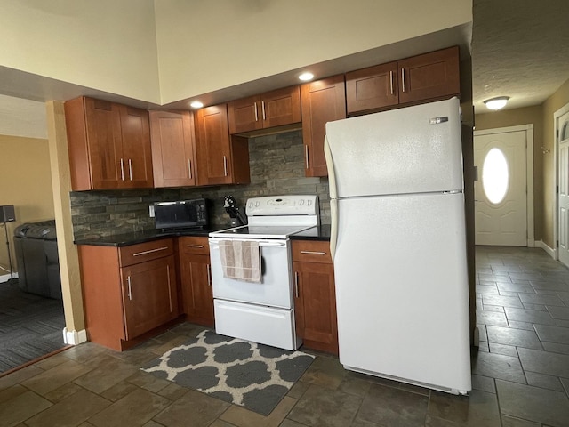 kitchen featuring dark countertops, backsplash, white appliances, and stone finish floor