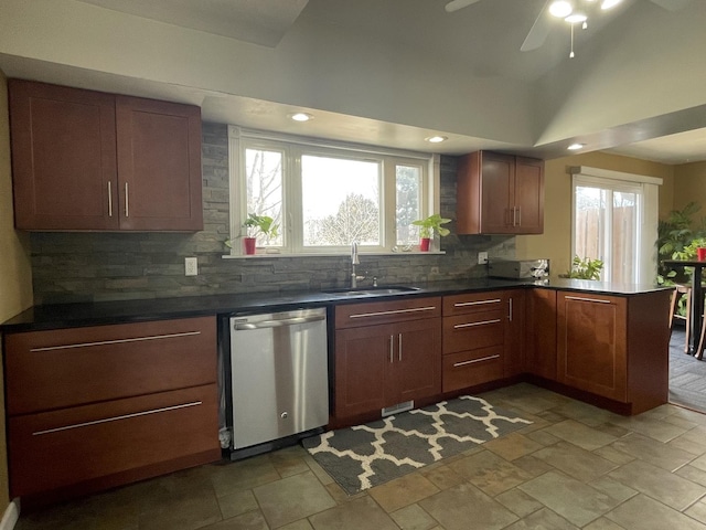 kitchen with dark countertops, dishwasher, decorative backsplash, a peninsula, and a sink