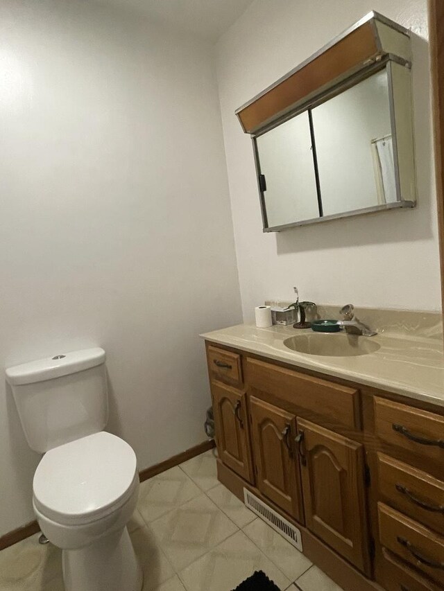 bathroom featuring visible vents, toilet, vanity, and baseboards