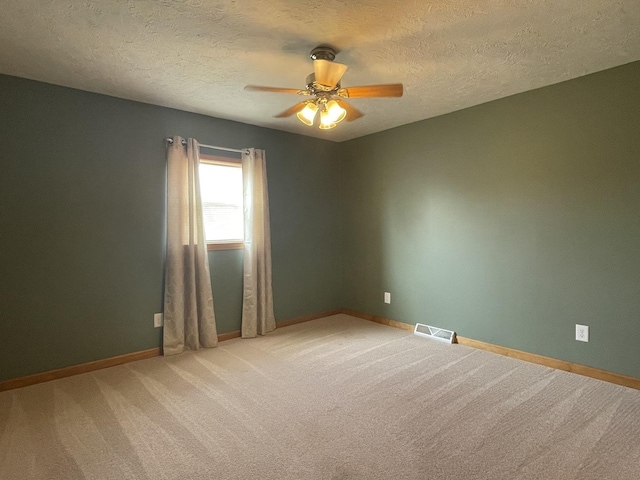 unfurnished room featuring visible vents, baseboards, ceiling fan, a textured ceiling, and light colored carpet