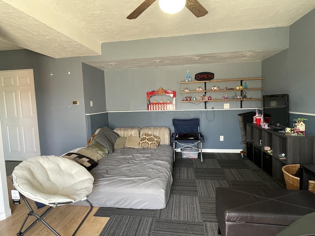 living area with baseboards, a textured ceiling, and a ceiling fan