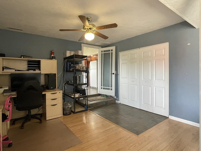 home office with ceiling fan, baseboards, a textured ceiling, and wood finished floors