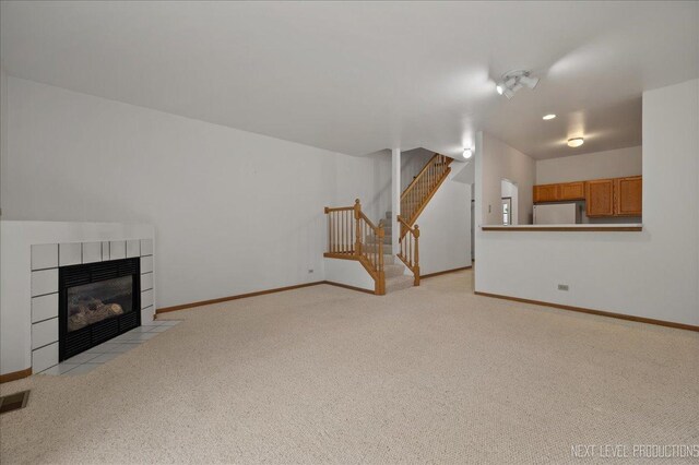 109 Oxford Ct Unit 0, Oswego, IL 60543 - unfurnished living room with light carpet, baseboards, stairway, and a tiled fireplace