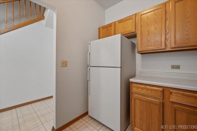 109 Oxford Ct Unit 0, Oswego, IL 60543 - kitchen with freestanding refrigerator, light flooring, light countertops, baseboards, and brown cabinets