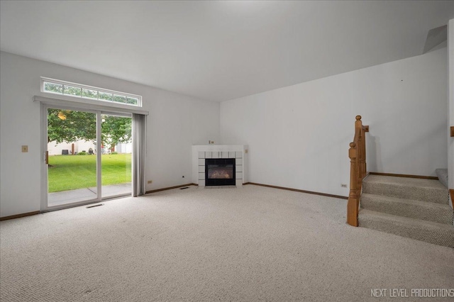 109 Oxford Ct Unit 0, Oswego, IL 60543 - unfurnished living room featuring carpet floors, baseboards, a tile fireplace, and stairs