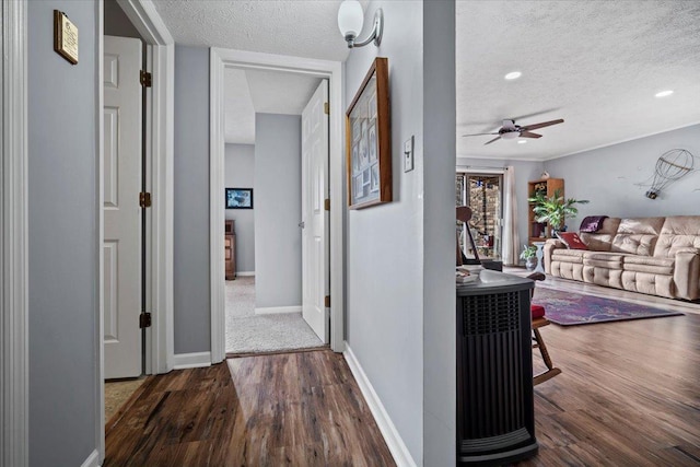 hallway featuring a textured ceiling, baseboards, and wood finished floors