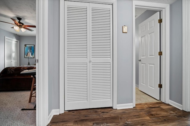 hall with dark wood-style floors, baseboards, and a textured ceiling