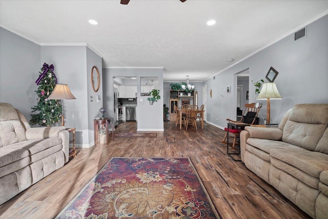 living room featuring visible vents, baseboards, wood finished floors, and ornamental molding